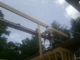 Carpenter setting a ridge beam over a new addition frame — Ice Dam Removal by Roofing Brothers in Sewell