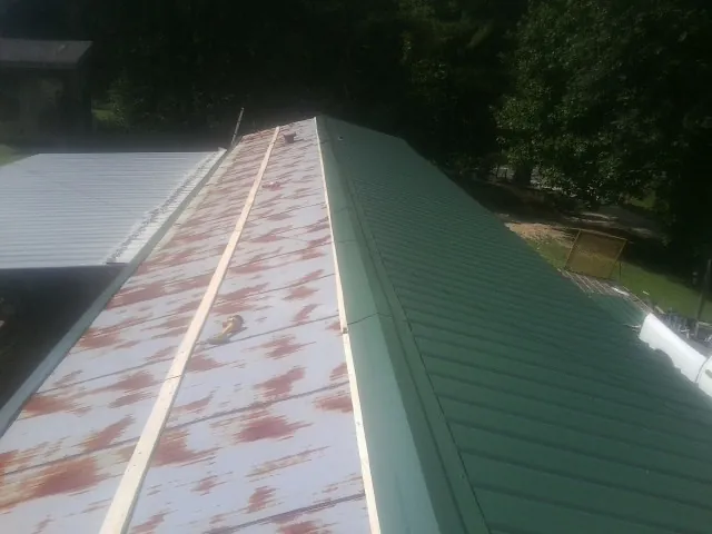 Old rusted panels beside newly installed green metal roofing — Wind Damage Roof Repair by Roofing Brothers in Sewell