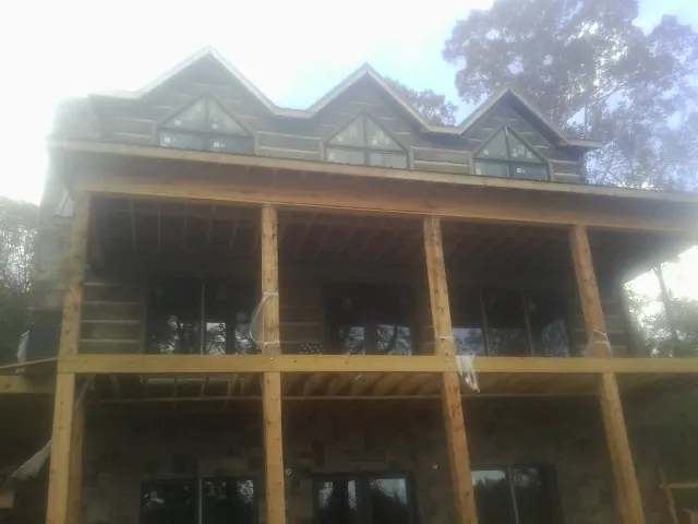 Dormers and porch framing on a large log home under construction — Roof Coating work by our crew in Sewell