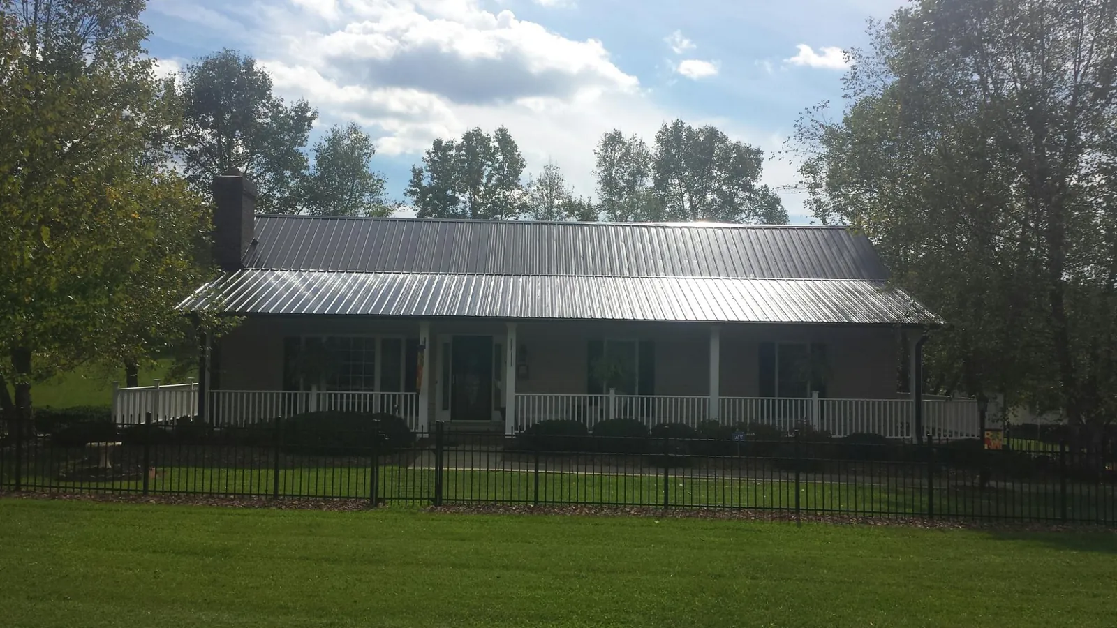 Gray metal roof on a brick ranch with a full width front porch — Gutter Guard Installation work by our crew in Sewell