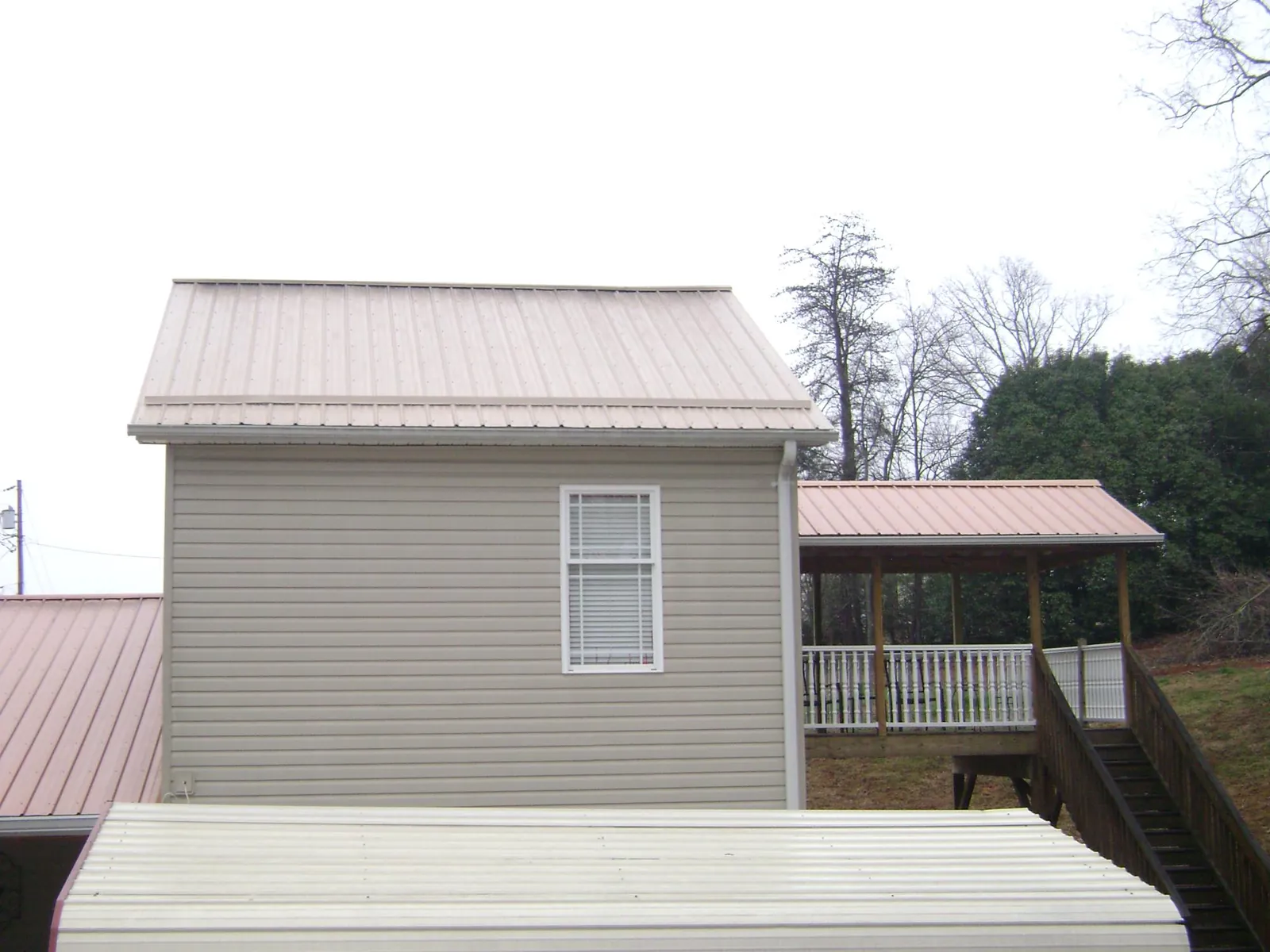 Tan metal roofs on a two story addition and attached porch, from a Roof Replacement job in Sewell