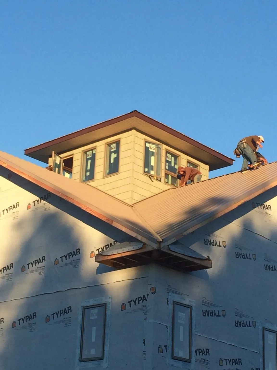 Roofers working around a rooftop cupola on a new metal roof at sunset — Roof Waterproofing in Sewell by Roofing Brothers